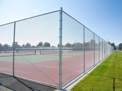 पॉलिमर-कोटेड टेनिस कोर्ट में डबल गेट के साथ बाड़ है।
